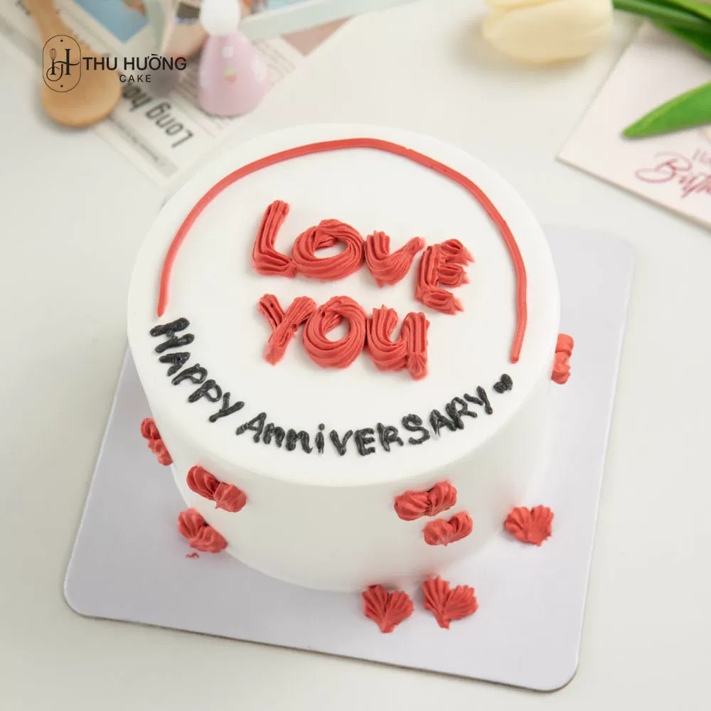 Bánh kem anniversary mini màu hồng nhạt, trang trí tinh tế với hoa và lá xanh