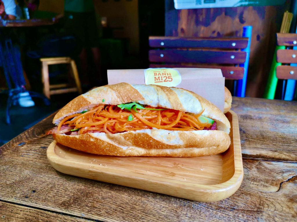 Bánh mì Hà Nội đầy ắp rau củ tươi và cà rốt cam rực rỡ, một ví dụ về hương vị bánh mì đặc trưng ngoài Hội An.