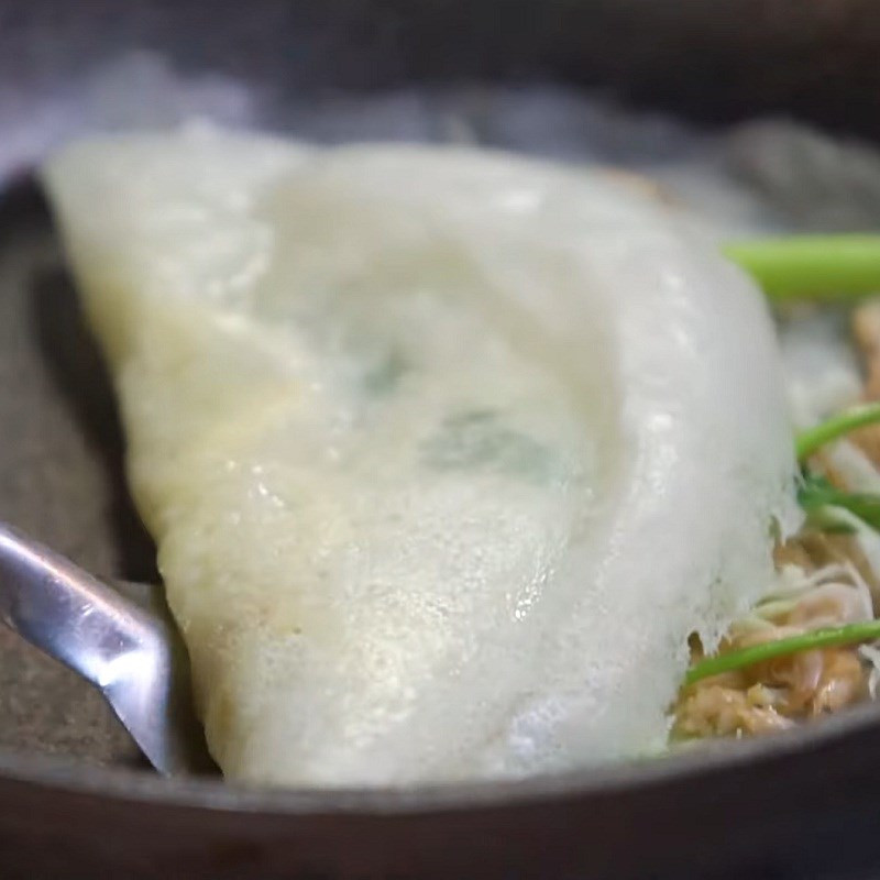 Đổ bánh khoái Thanh Hóa trên chảo, bánh đang được gấp đôi