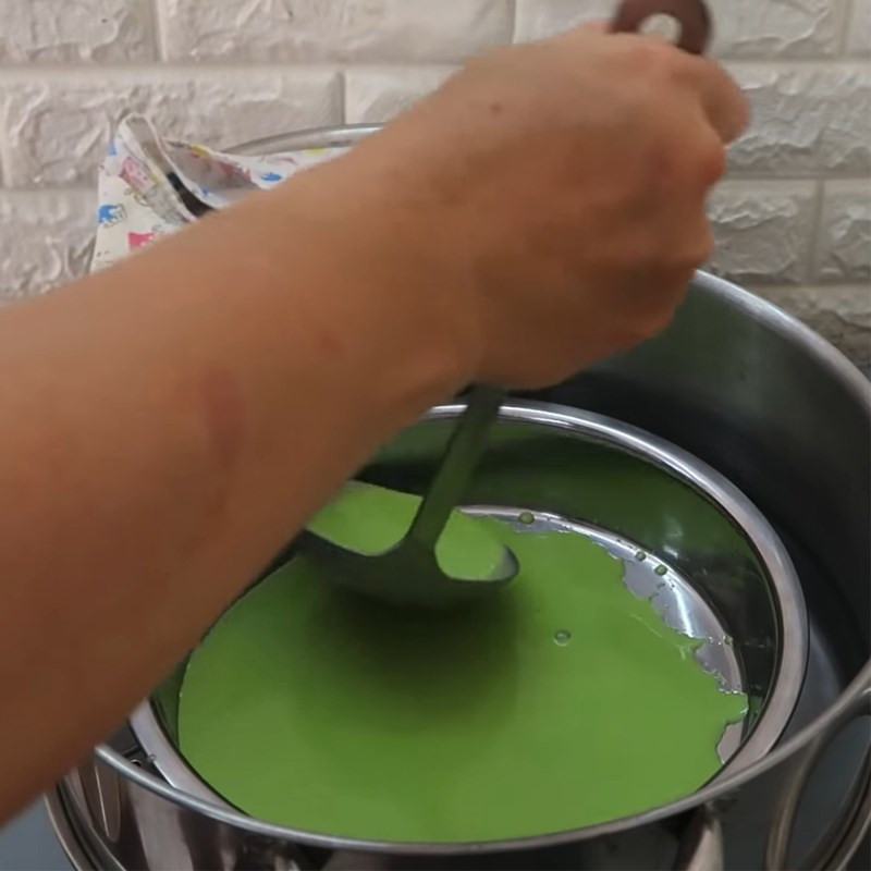 Đổ lớp bột trắng tiếp theo lên lớp xanh đã chín sơ của bánh da lợn truyền thống trong nồi hấp