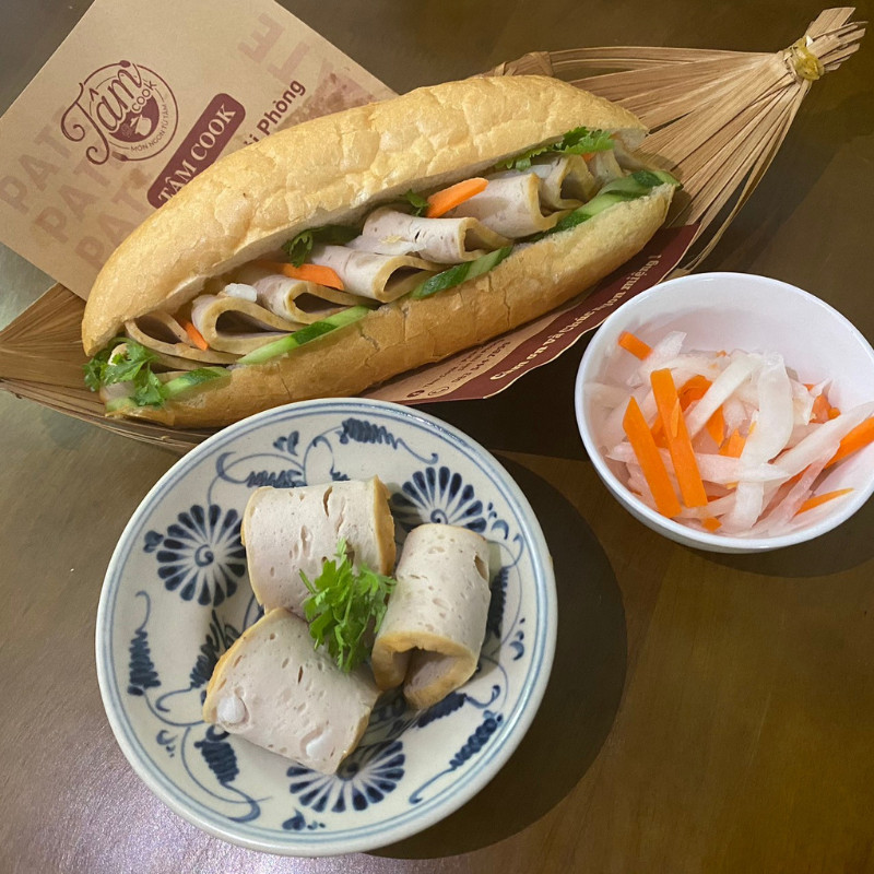 Hình ảnh bánh mì kẹp chả nóng được trang trí bắt mắt, thể hiện sự kết hợp hài hòa của các nguyên liệu tươi ngon.