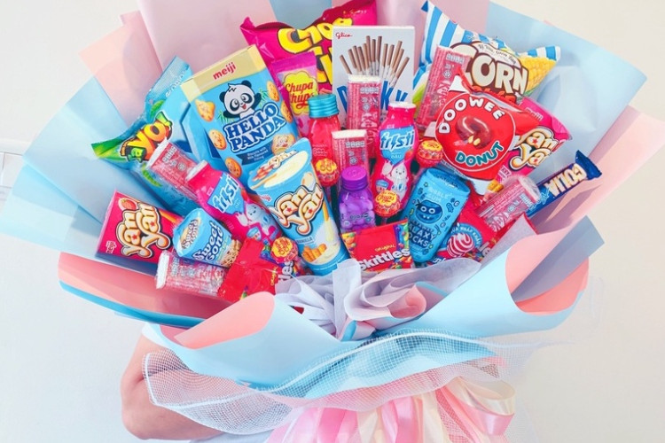 Một bó hoa bánh kẹo đẹp mắt được làm thủ công đang được cầm, thể hiện tình cảm của người tặng.
