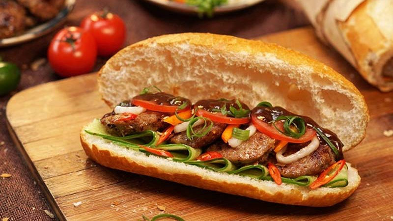 Một ổ bánh mì thịt nướng thơm ngon, cận cảnh các lớp thịt, rau, và pate, giúp người đọc hình dung rõ lượng calo trong từng thành phần