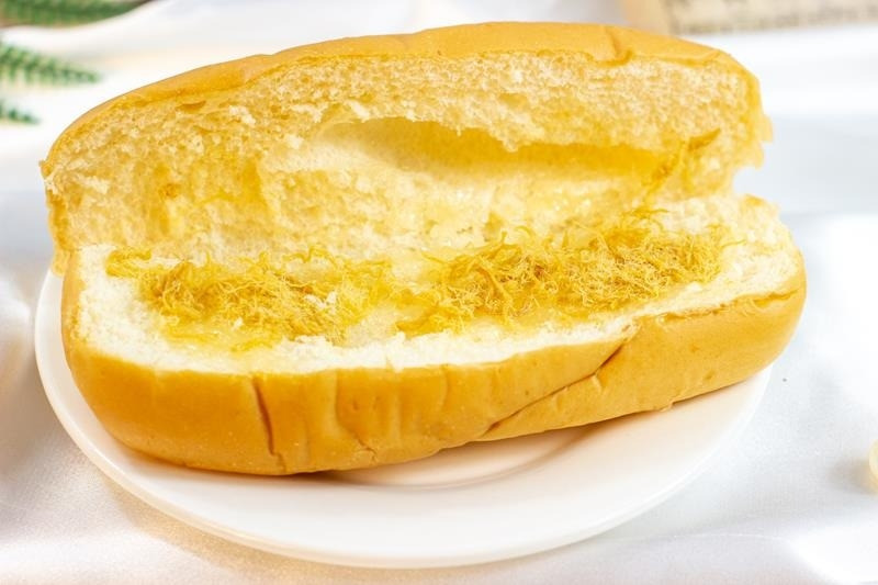 Một phần bánh mì bơ ruốc lớn đang được cầm trên tay