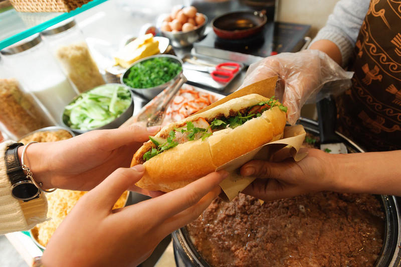 Người bán đang chuẩn bị bánh mì heo quay nóng hổi, một món ăn nhanh tiện lợi và cung cấp calo