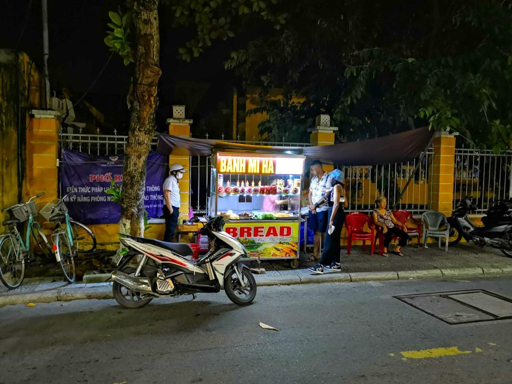 Người dân địa phương và du khách đang xếp hàng mua bánh mì Hội An tại xe đẩy Bánh Mì Hà, một góc phố quen thuộc.