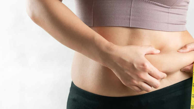 Người phụ nữ với vòng eo kém săn chắc đang kiểm tra eo bằng thước dây