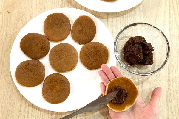 Phết nhân đậu đỏ vào giữa hai lớp vỏ bánh rán Doremon