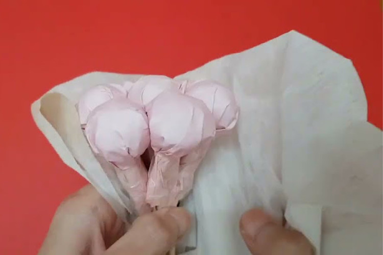 Quá trình gói nhiều lớp giấy xung quanh lõi bánh kẹo, định hình bó hoa bánh kẹo.
