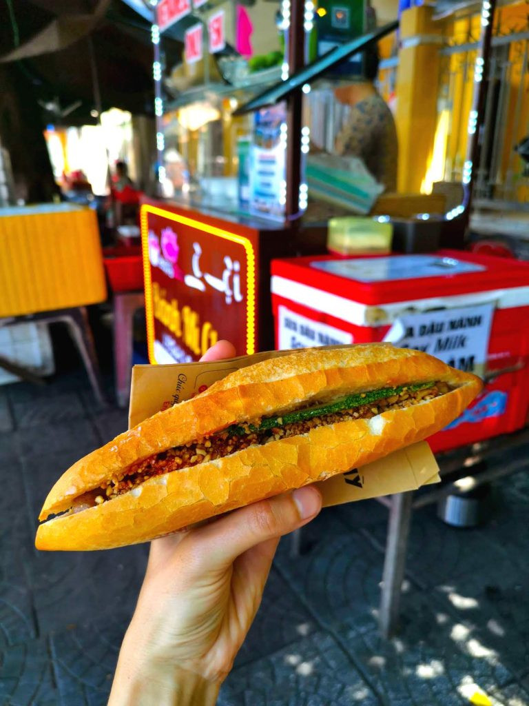 Thực khách đang cầm chiếc bánh mì chay Hội An tươi ngon, một lựa chọn lý tưởng tại Lê Hội Mì Chay dành cho người ăn thuần chay.