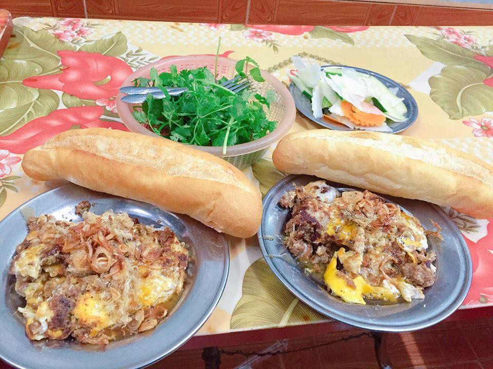 Bàn tay đang kẹp thêm nhân vào ổ bánh mì giòn rụm tại Nam Định