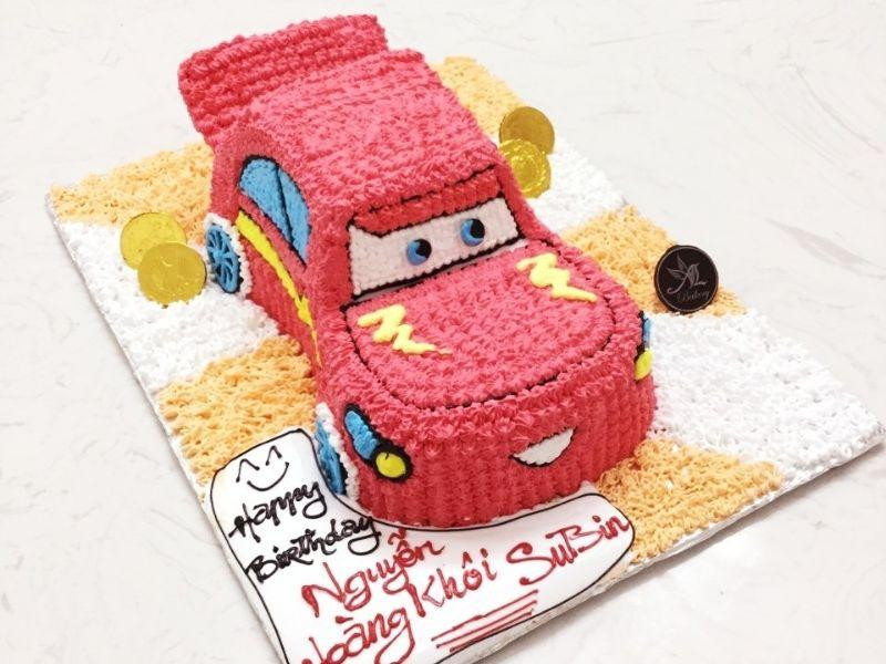 Bánh kem sinh nhật 2 tầng cho bé trai với thiết kế đoàn xe ô tô nhiều màu sắc, trên nền bánh ngọt ngào.