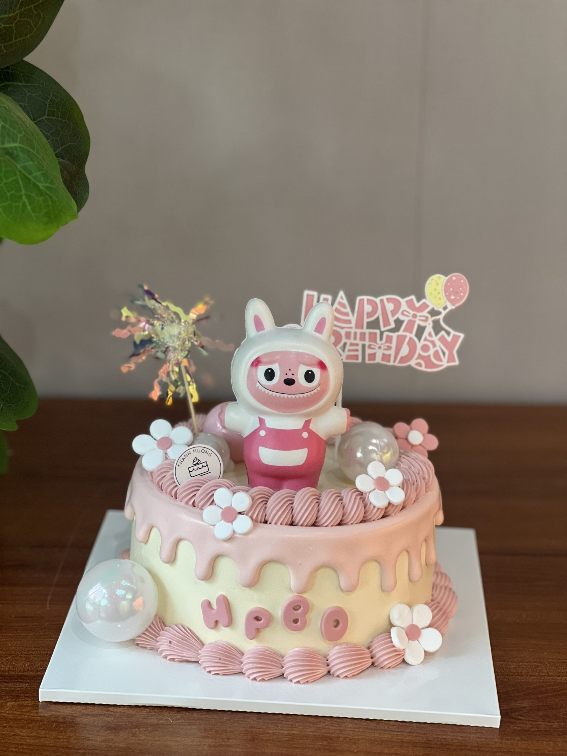 Bánh sinh nhật con gái hai tầng với họa tiết hoa lá và động vật dễ thương, phù hợp cho tiệc lớn.