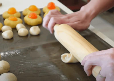 cuộn bột thành hình trụ để chuẩn bị cho vỏ bánh pía nhiều lớp