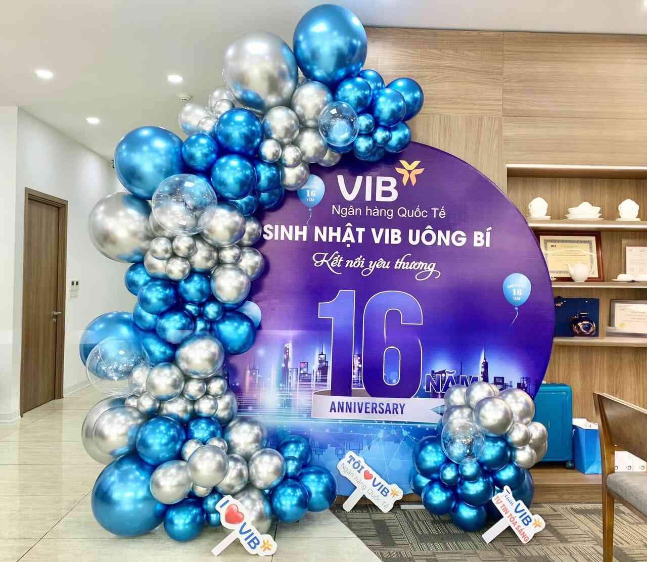 Không gian tiệc sinh nhật công ty với bóng bay và bánh kem đa tầng