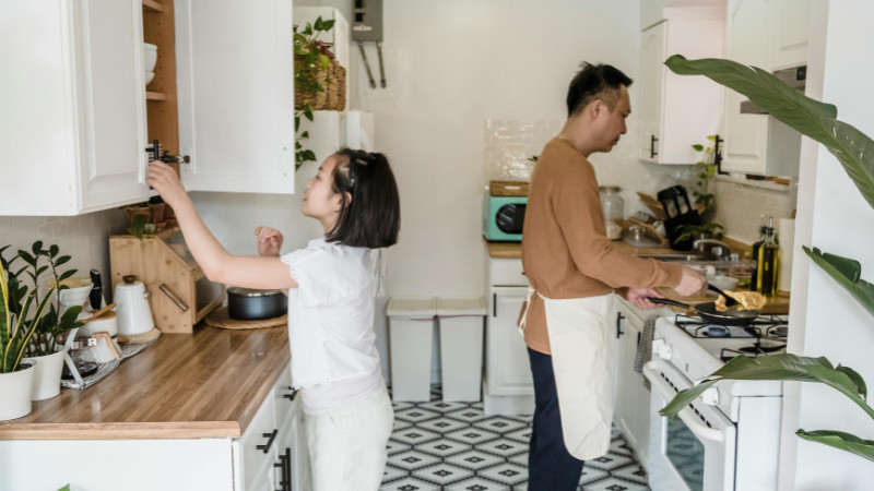Người đàn ông đang giúp người phụ nữ làm việc nhà bằng cách lau dọn bàn ăn, thể hiện sự quan tâm và sẻ chia